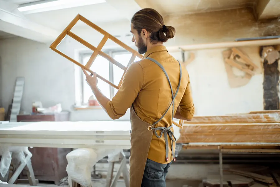 Un menuisier vérifie un cadre de fenêtre à l’atelier : décrire aussi précisément son métier permet de comparer des réponses qui parlent du même site.