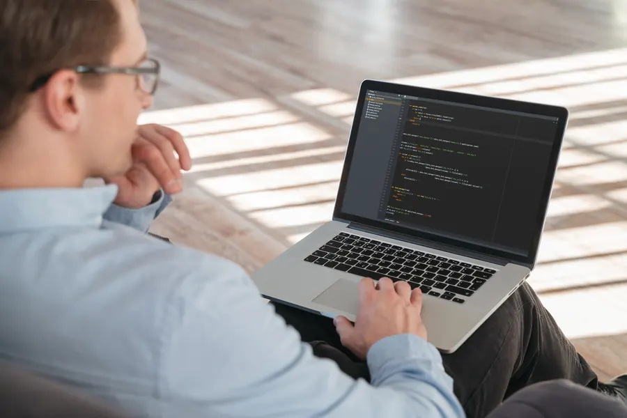 Un développeur examine le code d’un site sur son ordinateur portable : l’état de départ doit être connu avant de chiffrer la maintenance.