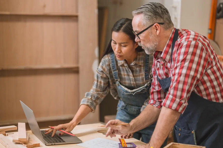 Un artisan et une webdesigner regardent ensemble une maquette à l’écran, dans l’atelier : c’est à ce stade qu’un changement de direction coûte le moins de temps.
