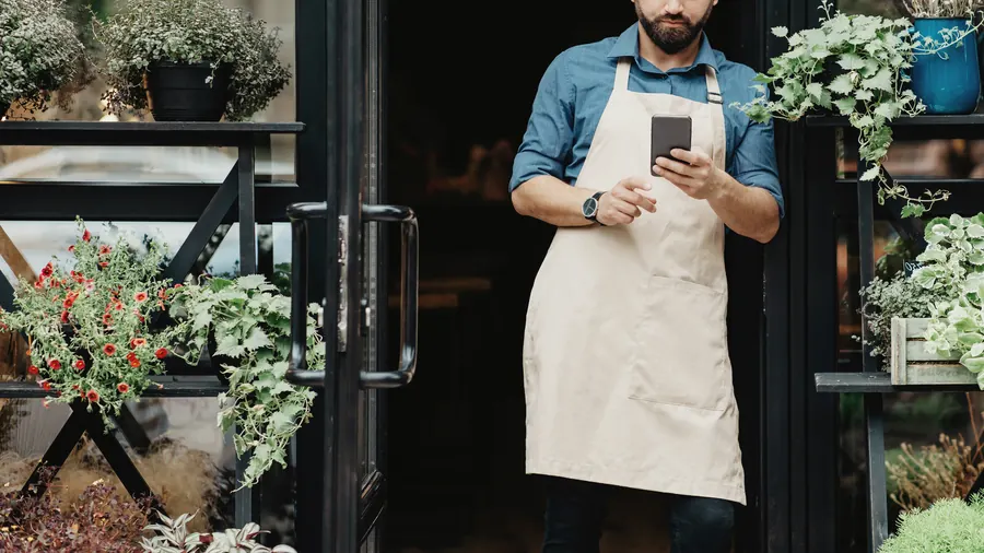Un commerçant, téléphone en main sur le pas de sa porte, découvre que sa fiche n’apparaît plus : avant de réagir, lisez le motif indiqué par Google.