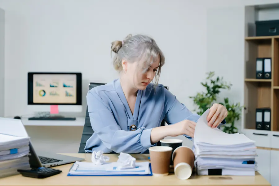 Une gérante trie ses documents administratifs à son bureau : extrait d’immatriculation et facture au bon nom, à la bonne adresse, sont prêts avant d’ouvrir le formulaire d’appel.