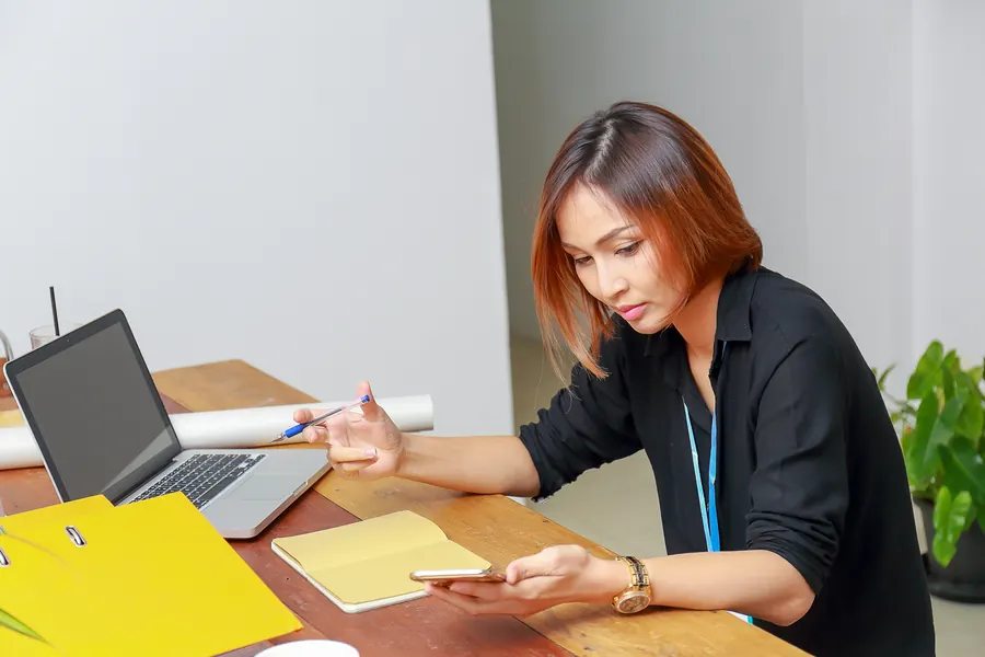 Une gérante vérifie ses messages à son bureau : sans test régulier, rien ne lui signale que des demandes se perdent en route.