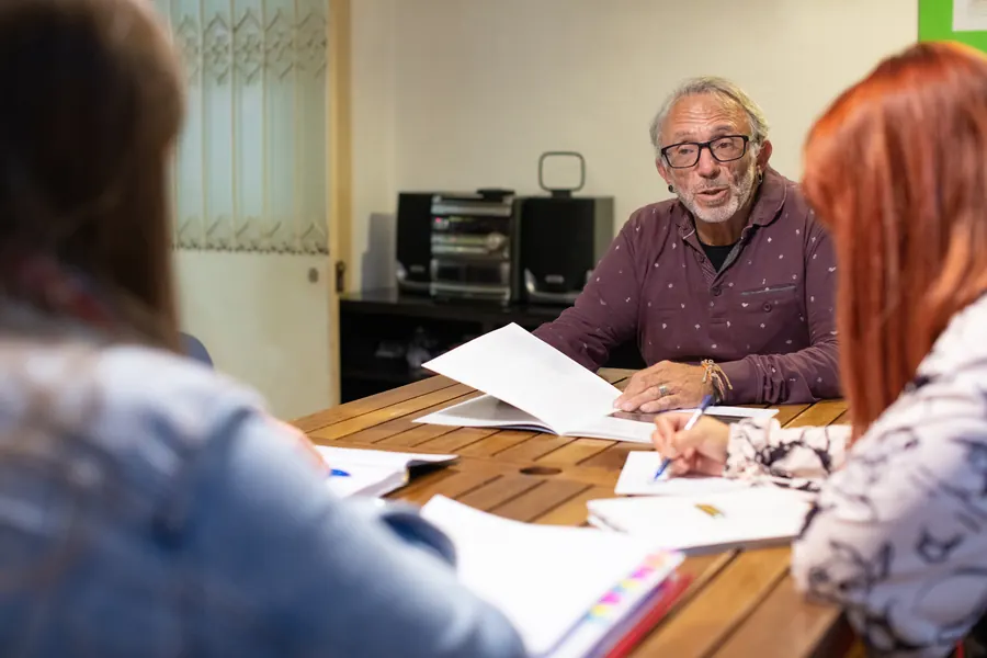 Une réunion de travail autour d’une table couverte de documents : propriété du domaine, réversibilité et maintenance se fixent par écrit, avant la commande.