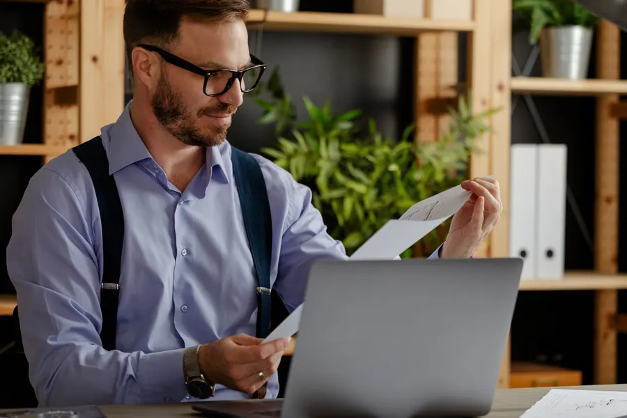 Un artisan relit des documents administratifs devant son ordinateur