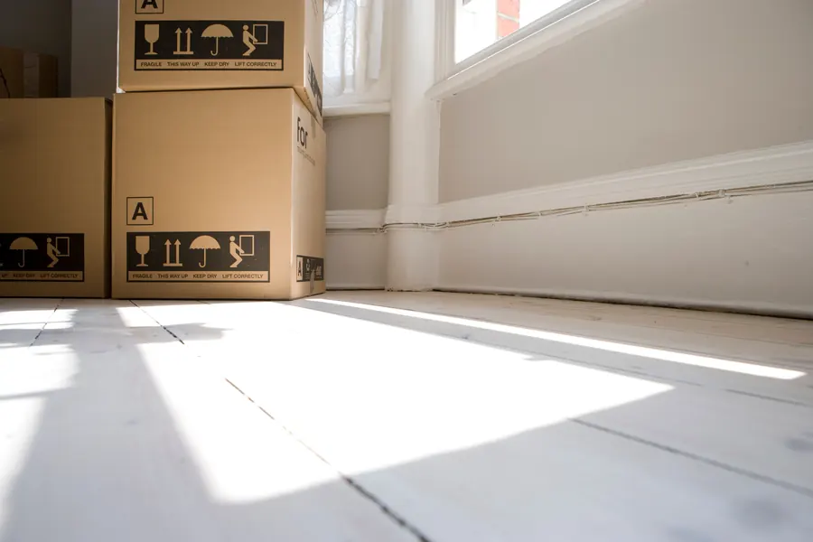 Cartons de déménagement empilés dans une pièce baignée de lumière