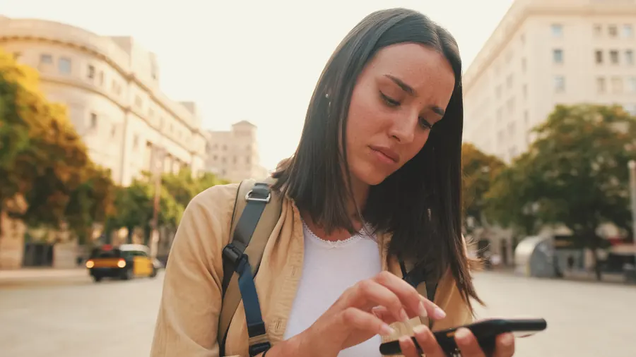 Voyageuse consultant son smartphone dans une rue ensoleillée
