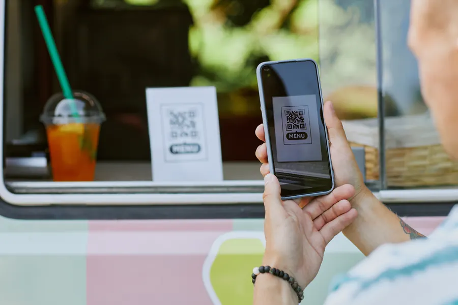Un QR code posé sur le comptoir d’un food truck : lu à bout de bras, parfois en plein soleil, il doit être grand, contrasté et mener à une page qui s’affiche vite.