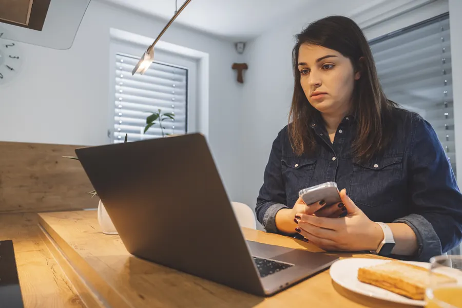 Une femme compare ce qu’affichent son téléphone et son ordinateur : la même question, posée deux fois, ne reçoit pas toujours la même réponse.
