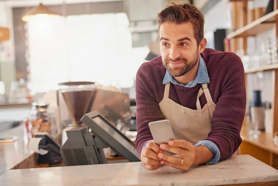 Un gérant de café interroge une IA depuis son téléphone : poser la question que poserait un client reste le test le plus simple.