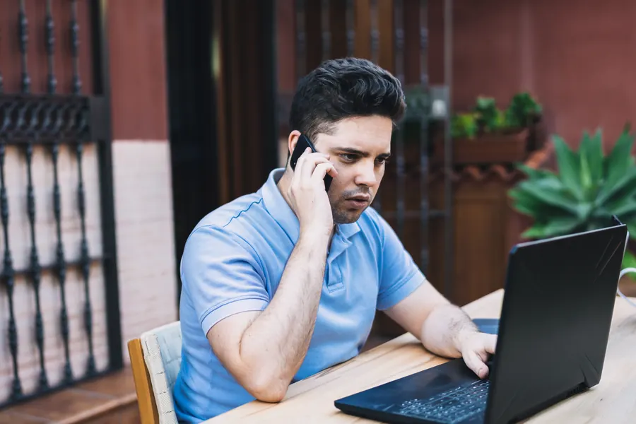 Un homme au téléphone devant son ordinateur : ces premiers gestes se font souvent guidés à distance, avant tout nettoyage.