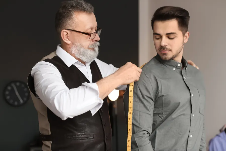 Un tailleur prend les mesures d’un client : un site conçu pour vous part de votre activité, là où un thème tout fait vous demande de vous adapter à lui.