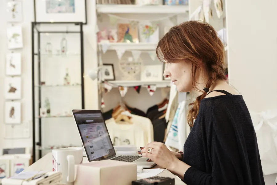 Une commerçante met à jour son site depuis sa boutique : pour un site simple qu’on gère soi-même, un constructeur en ligne peut suffire.