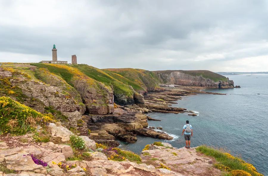 Randonneur face au phare du cap Fréhel, dans les Côtes-d’Armor