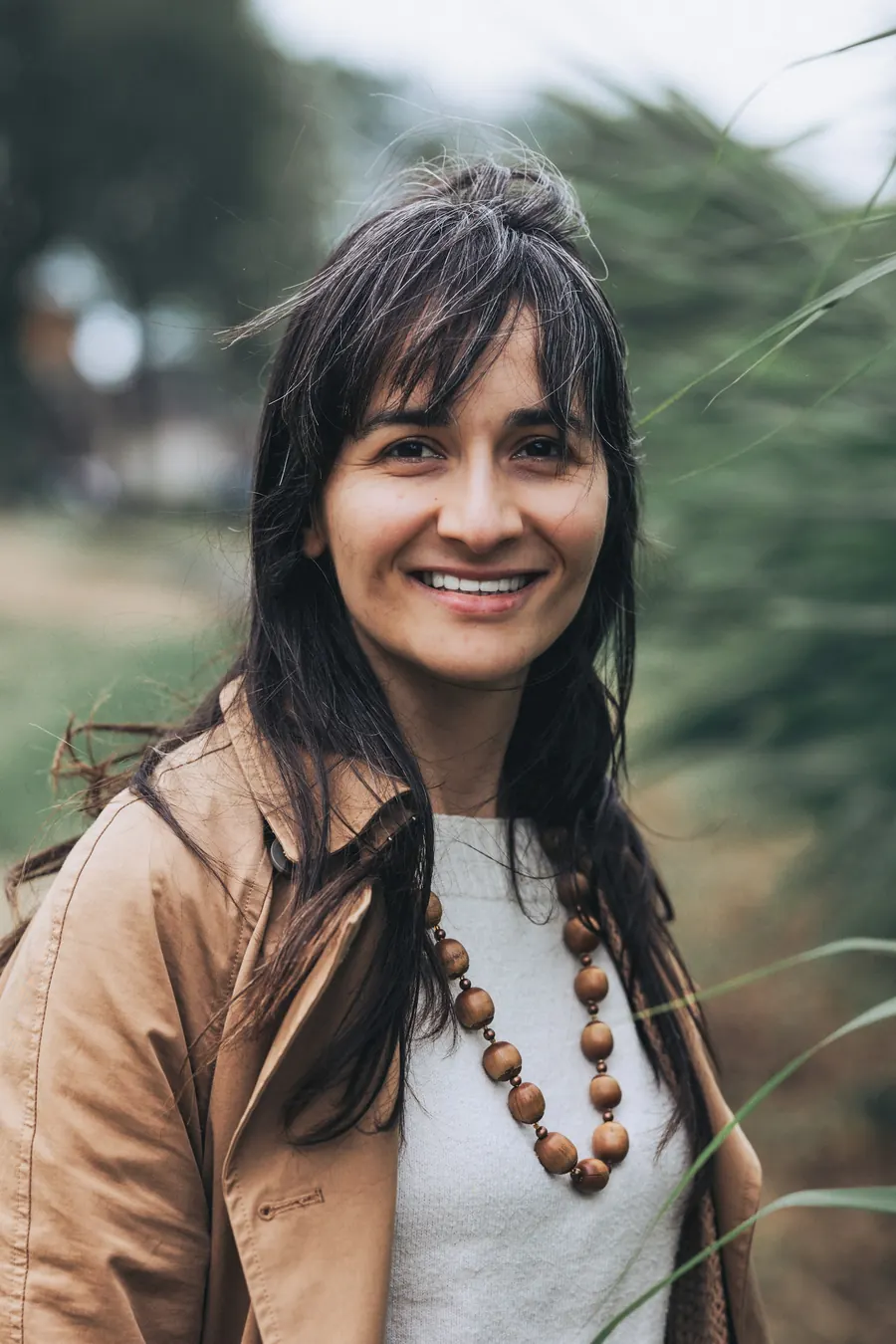 Femme brune souriante en extérieur, sans carnet visible