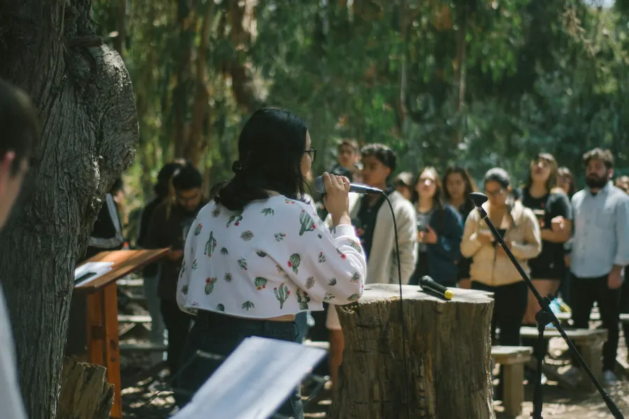 Femme qui prend la parole devant un groupe réuni en plein air sous les arbres