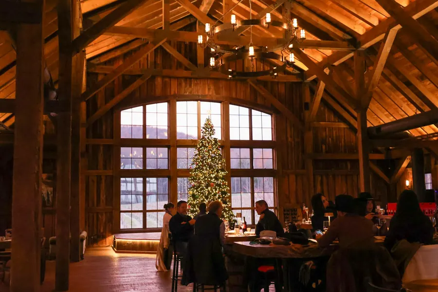 Salle en bois avec charpente apparente, dîner de groupe et sapin de Noël