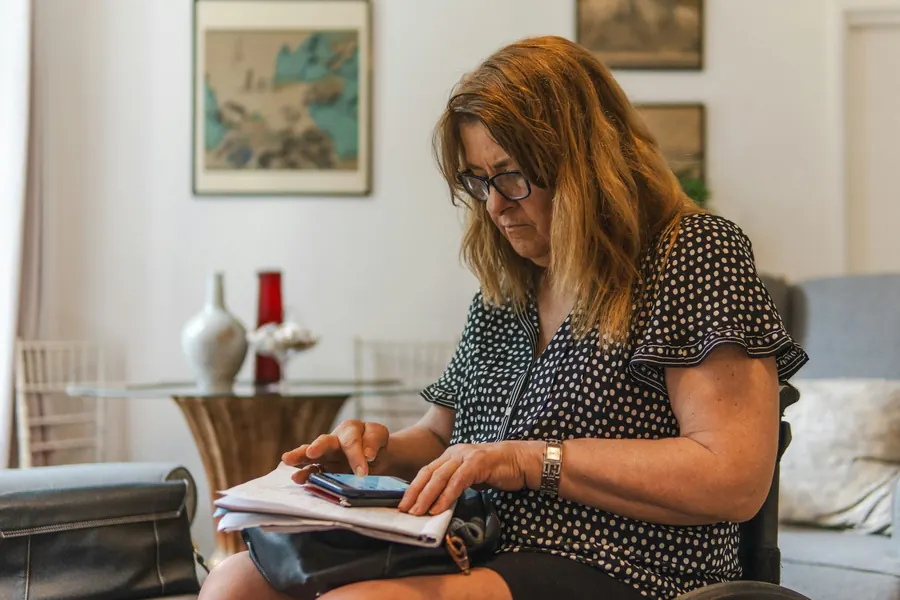 Femme qui consulte des documents et son téléphone dans un salon