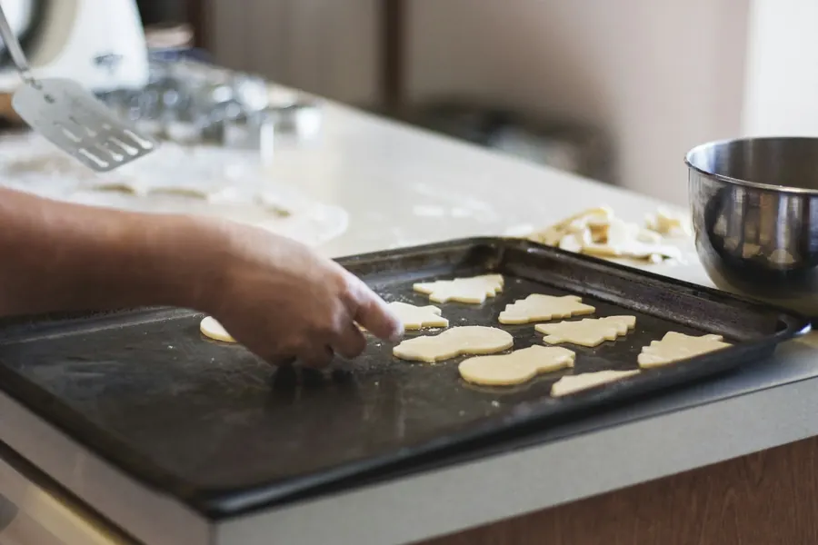 Vue de dessus d'une recette en cours avec des biscuits, mains, plan de travail en bois