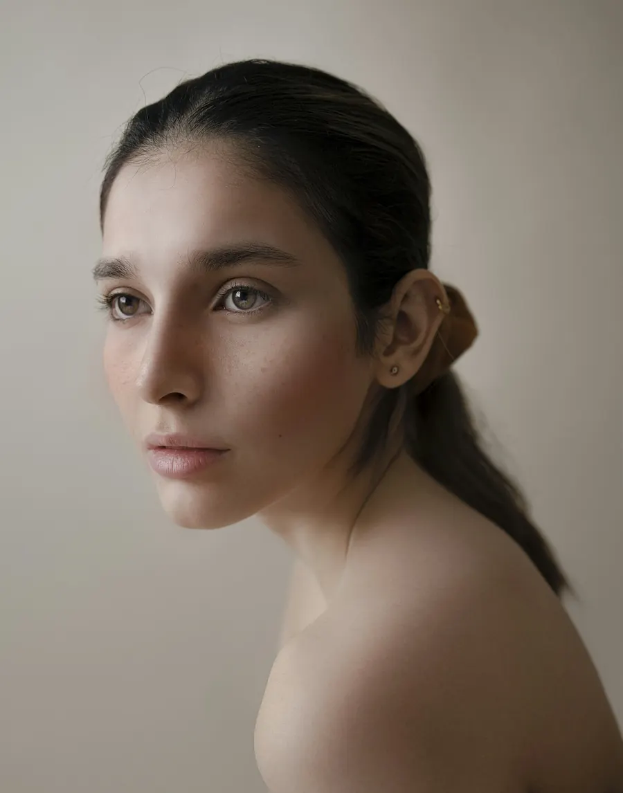 Portrait de mannequin femme en studio à la lumière du jour, fond blanc, sans artifice