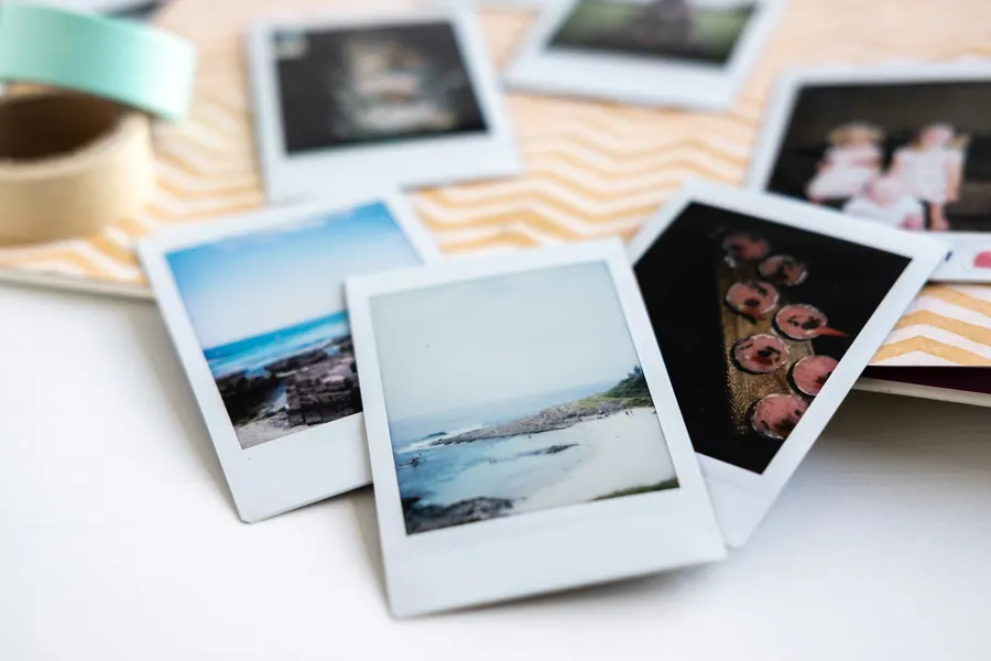Plusieurs photos polaroïd éparpillées sur une table blanche