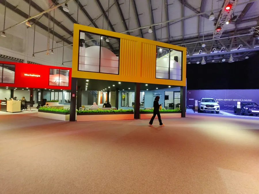 Stand à étage en conteneurs jaune et rouge dans un hall d'exposition presque vide