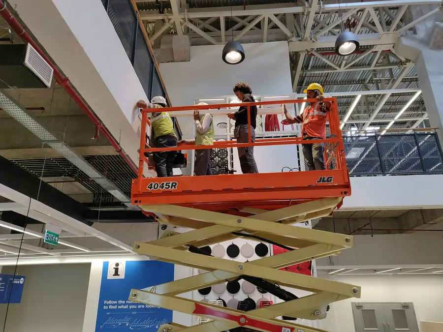 Monteurs qui assemblent un grand stand de nuit dans un hall, nacelle et caisses ouvertes