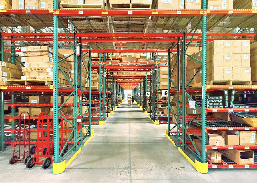 Entrepôt avec racks et caisses étiquetées au nom des exposants