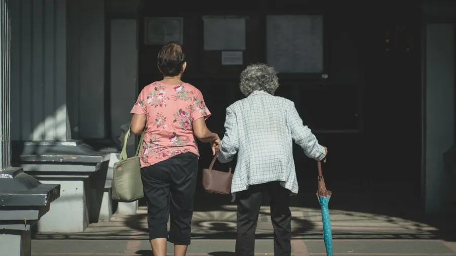 Deux femmes de dos qui marchent ensemble dans la rue, sacs à la main