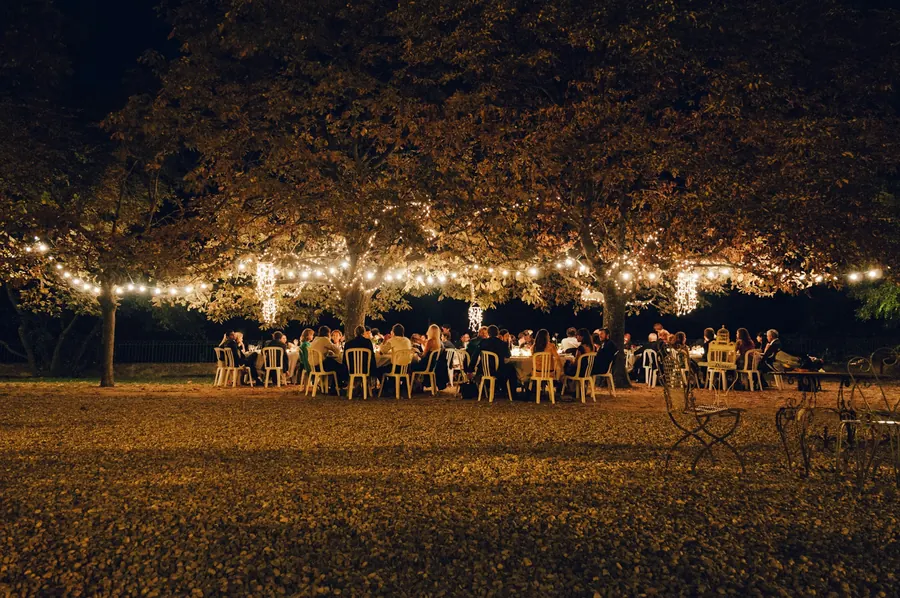 Dîner en plein air le soir sous des arbres illuminés de guirlandes