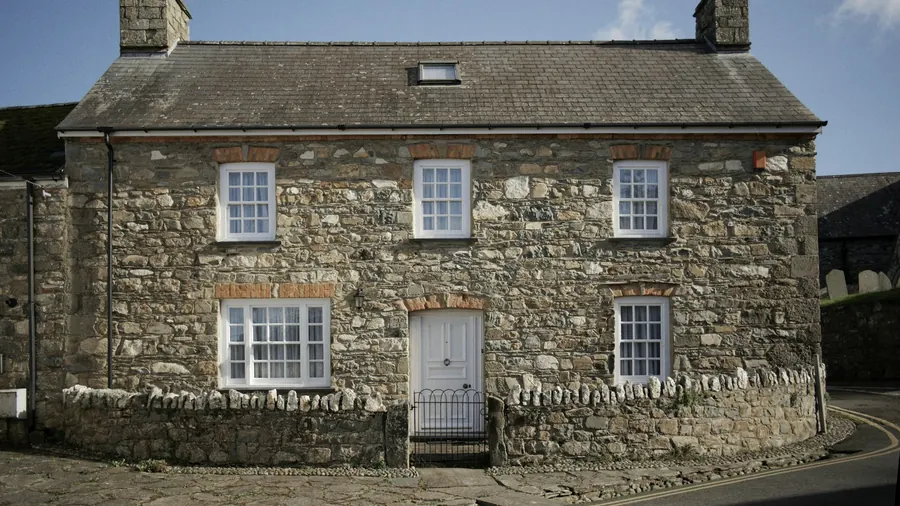 Maison en pierre à deux étages en bon état, avec fenêtres à petits carreaux