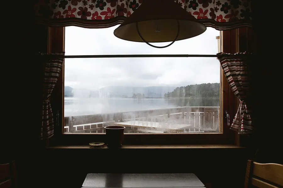 Vue sur un lac depuis une fenêtre de chalet en bois