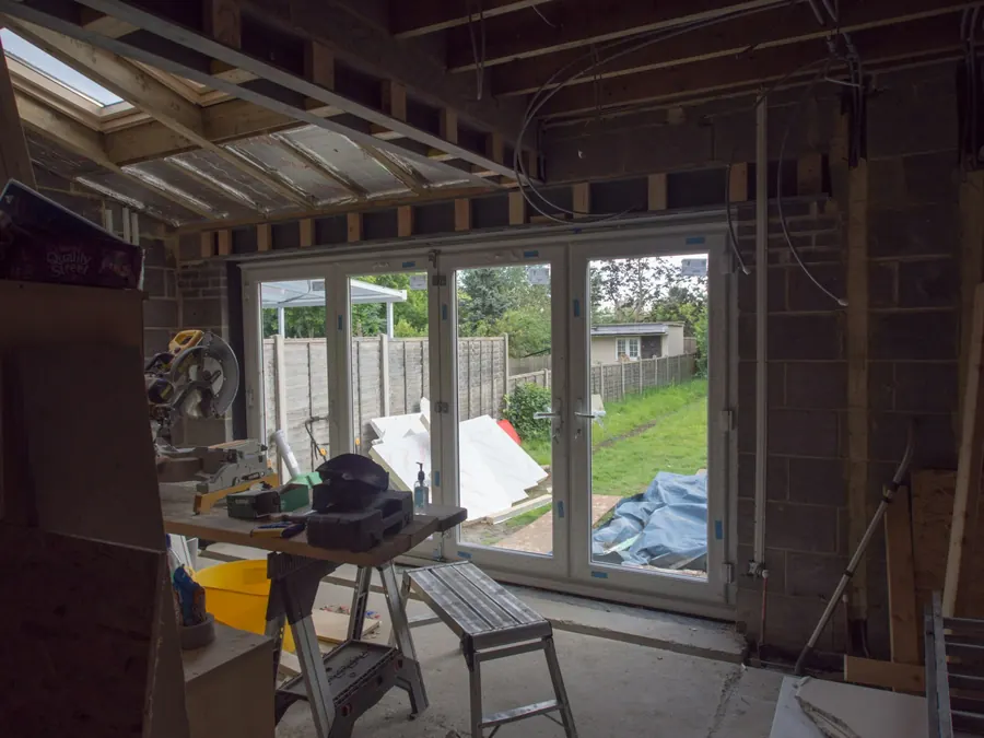Intérieur d'une extension en construction, portes vitrées sur jardin