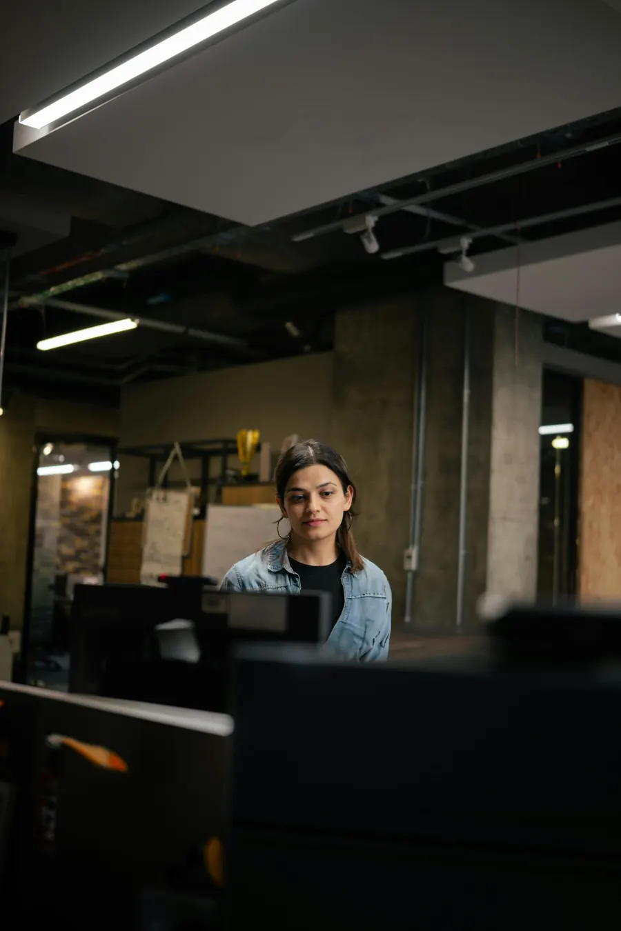 Femme au bureau dans un atelier d'architecture, écran d'ordinateur sombre, pas de maquette visible