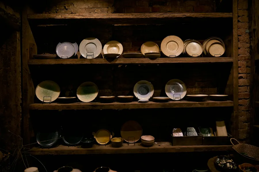 Bols et tasses faits main qui sèchent sur des étagères en bois, atelier modeste