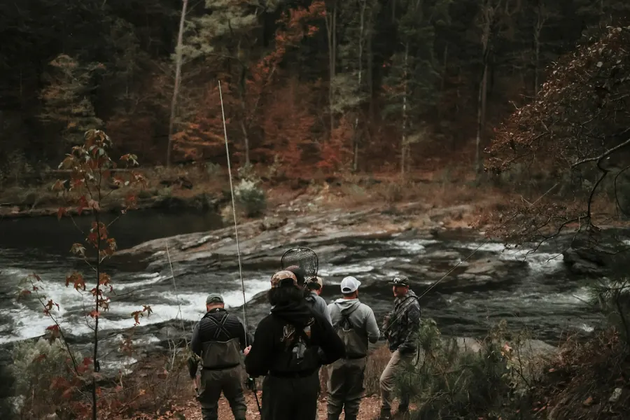 Groupe de randonneurs sur un chemin au bord d'une rivière calme, feuillage d'automne