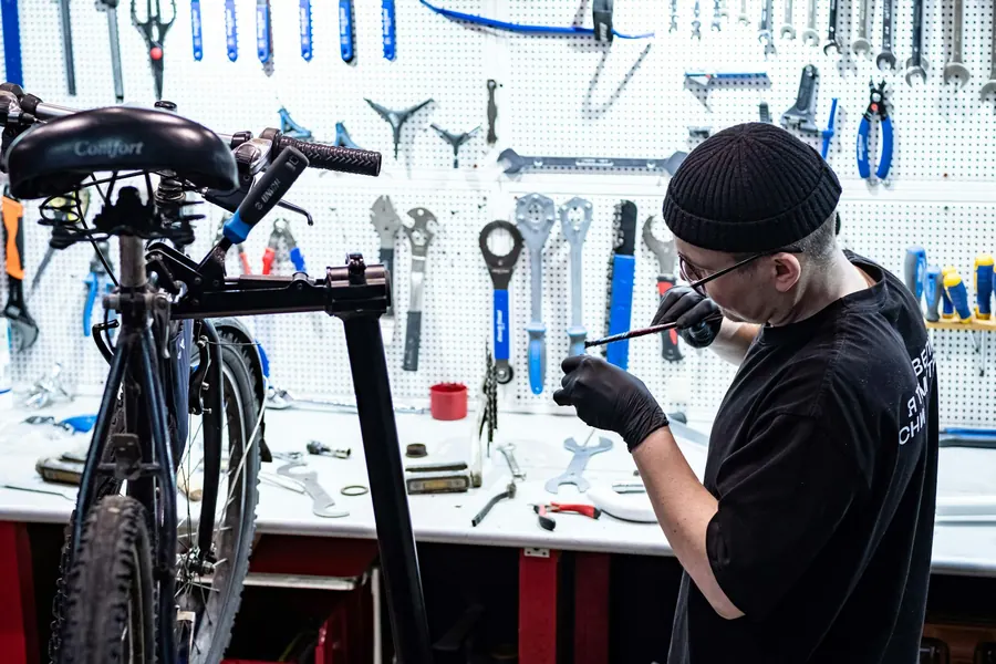 Homme réparant un vélo sur pied d'atelier, seul, sans adolescente présente