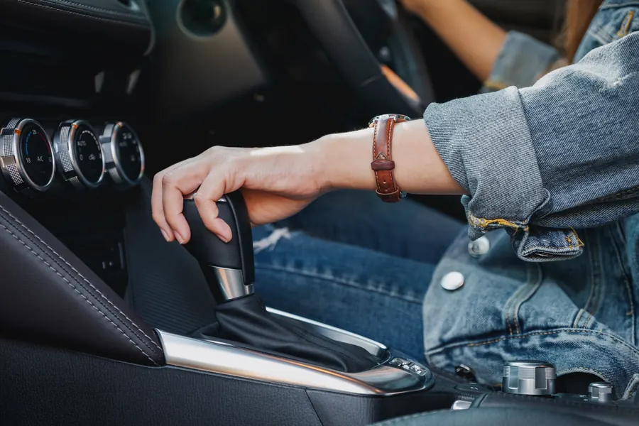 Main d'une jeune conductrice sur un levier de boîte automatique