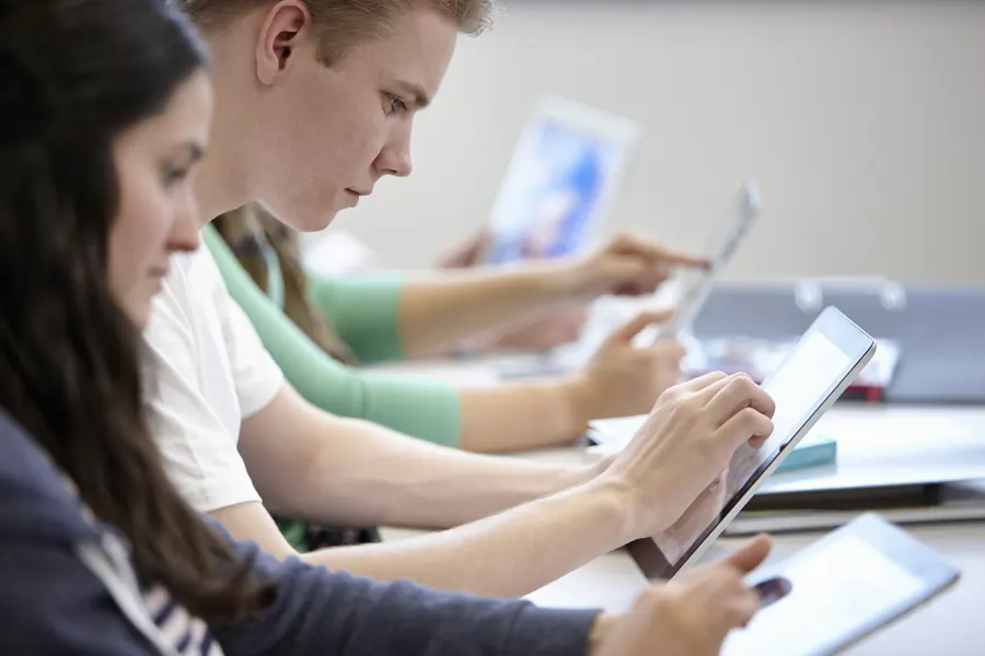 Élèves en salle de code, tablettes et écran de questions
