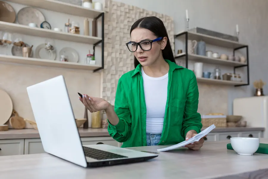 Cliente en visioconférence avec son avocate, ordinateur portable sur la table de cuisine