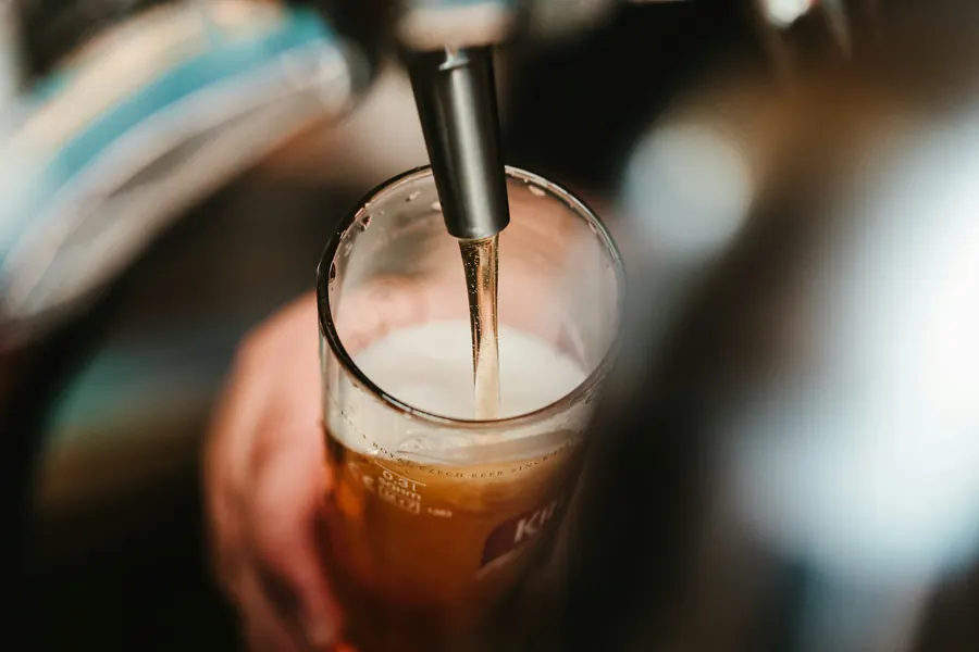 Mains d'un barman qui tire une pression, comptoir en métal, pas de client au premier plan