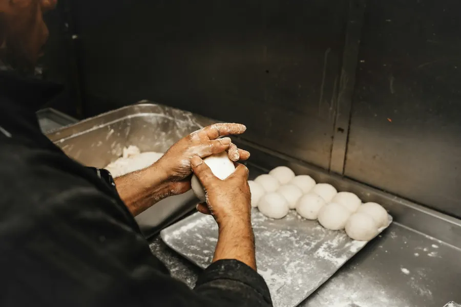 Boulanger qui façonne des pâtons au levain dans le fournil, de nuit