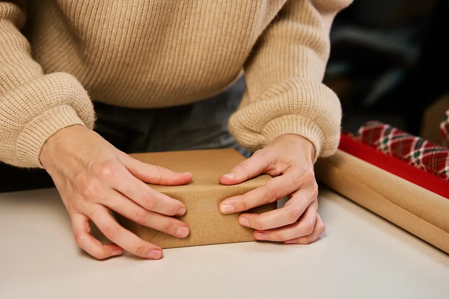 Mains qui emballent un colis en papier kraft sur le comptoir