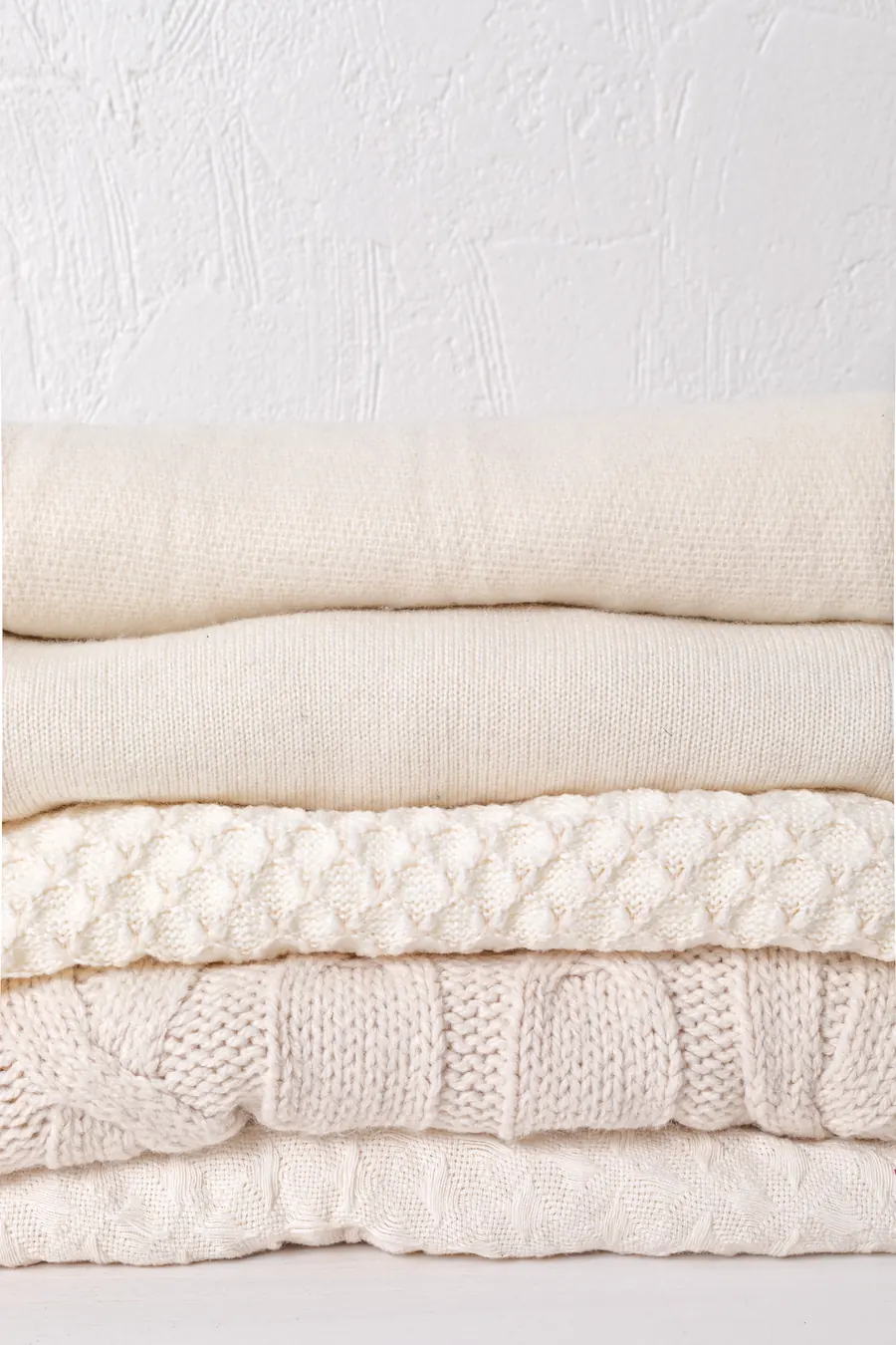 Pull marin écru plié, grosse maille visible, lumière du jour