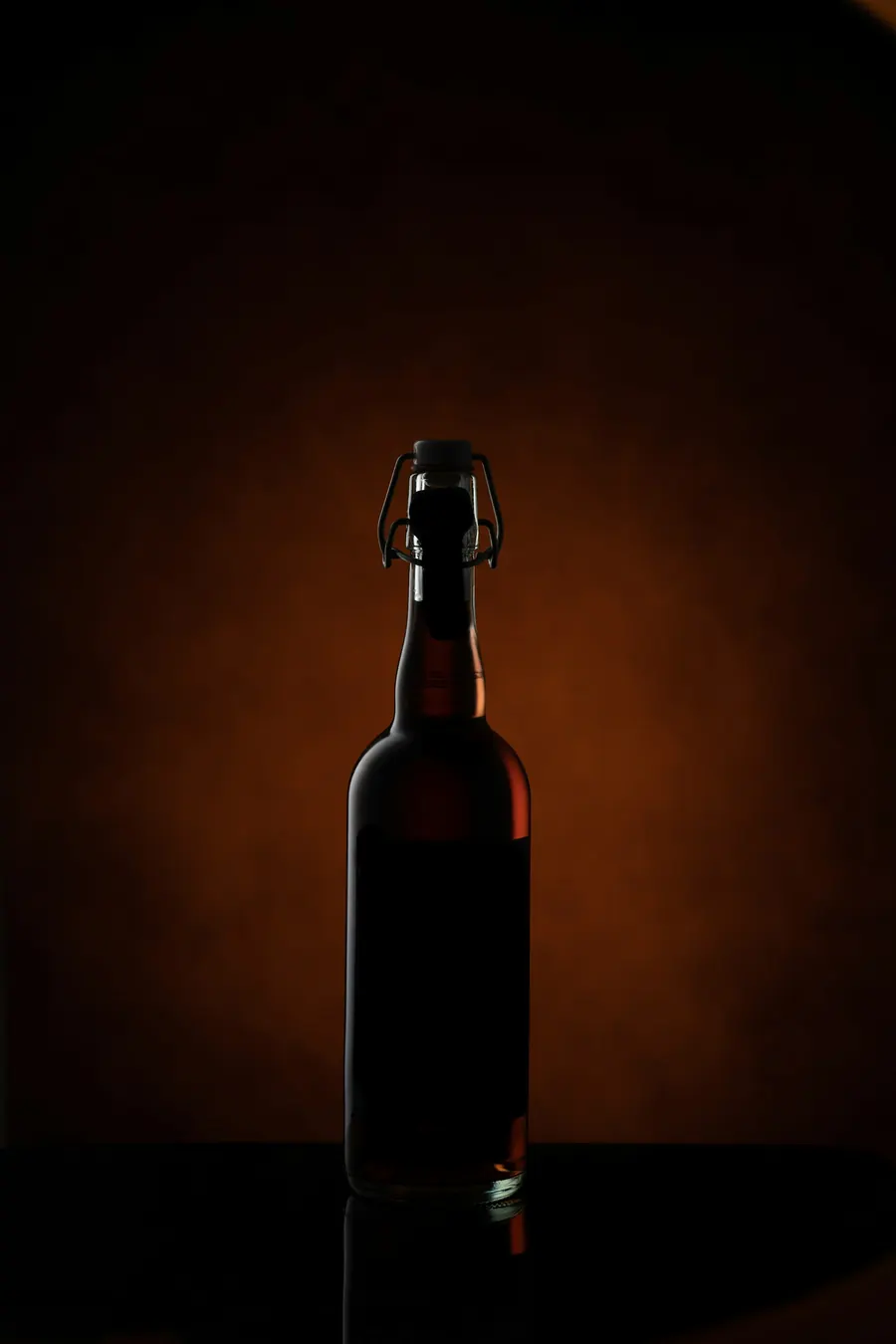Bouteille brune à bouchon mécanique sur fond brun uni, sans grains de malt