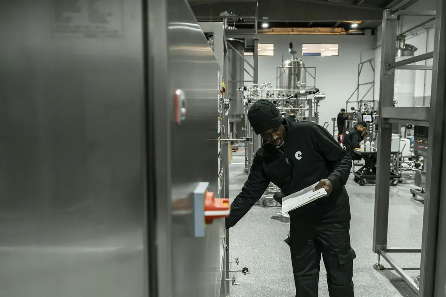 Un homme inspectant l'équipement près des cuves en inox, atelier industriel