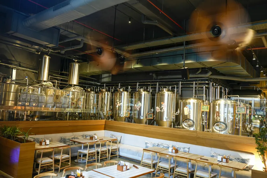 La taproom vide avant l'ouverture, tables en bois, cuves au fond
