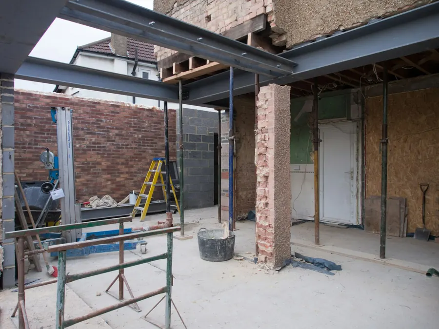 Ouverture de mur porteur soutenue par des poutres acier et des étais, chantier de rénovation
