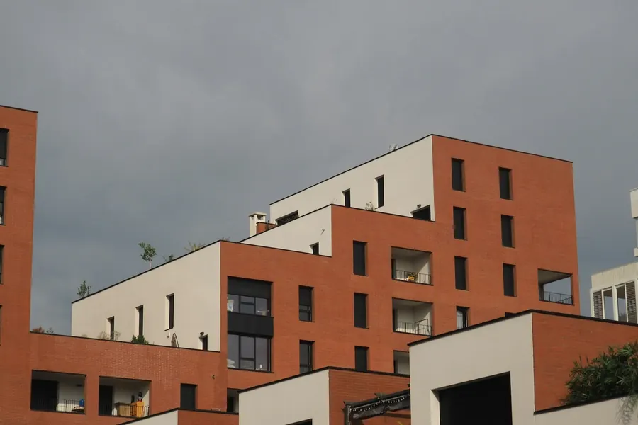 Immeuble récent en briques rouges avec balcons et garde-corps