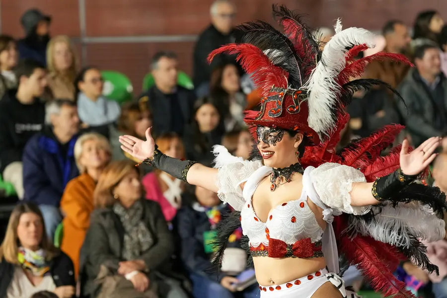 Danseuse en costume à plumes rouges et blanches devant un public assis