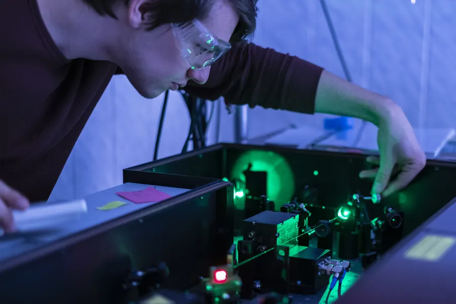 Technicien sur un banc optique, fibres et lasers